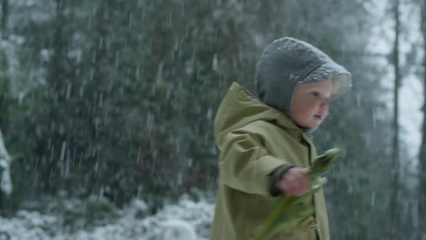 A boy plays outside in a snow storm with his mom