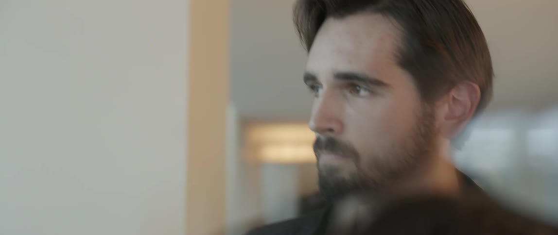 A bearded man looks down and then back up