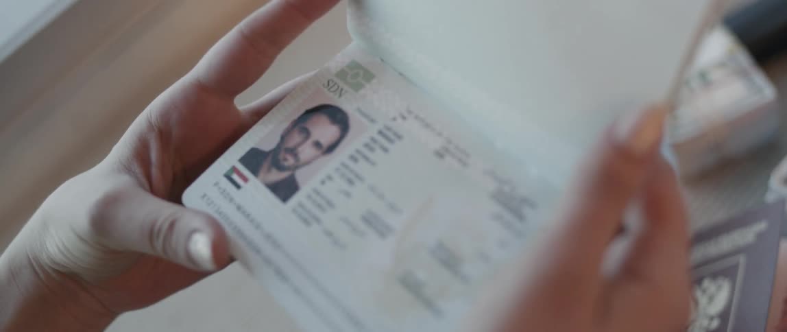 A woman looks at the photo page of a man's passport