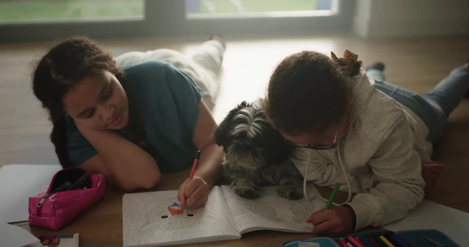 Two children color with the dog sitting inbetween