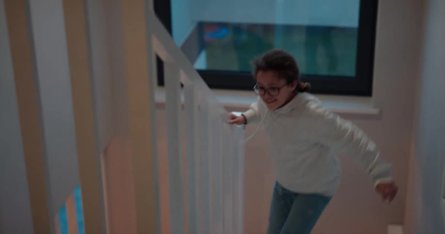 A girl quickly ascends a staircase in a house in the evening