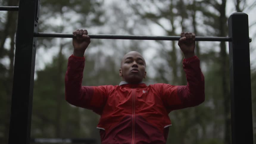 A man does pulls ups in a park