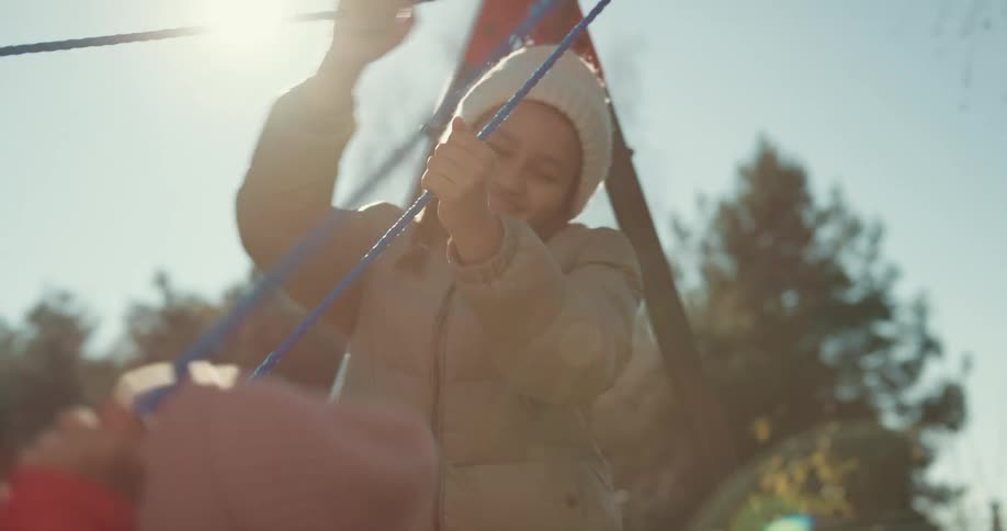 A girl pushes her friend on a swing in a back yard