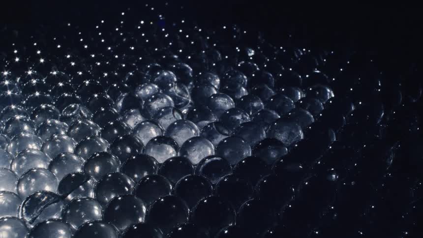 Light reflecting over translucent transparent glass spheres piled up inside a dimly lit room