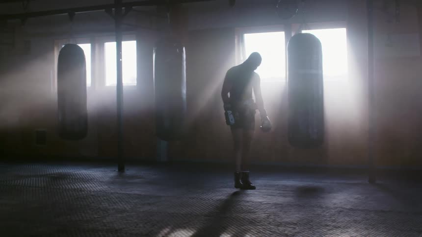 A boxer catches his breath and jumps on the spot before throwing punches at a boxing bag