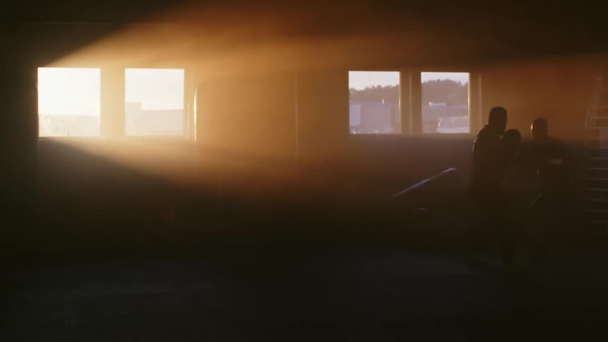 A box trainer by striking the mitts of a trainer in a dimly lit boxing gym