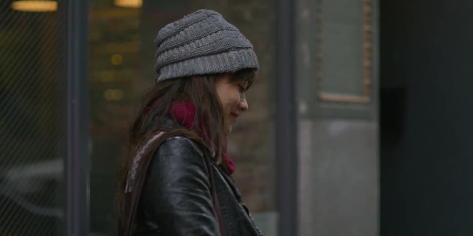 Woman opens yellow umbrella and walks along wet sidewalk downtown