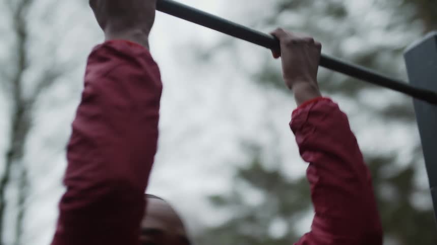 A man is doing pull ups outside