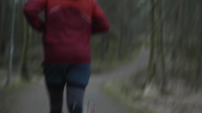 A man is jogging outdoors during spring in a forest