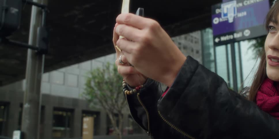 A woman in a city stands outside and takes a photo of a picture