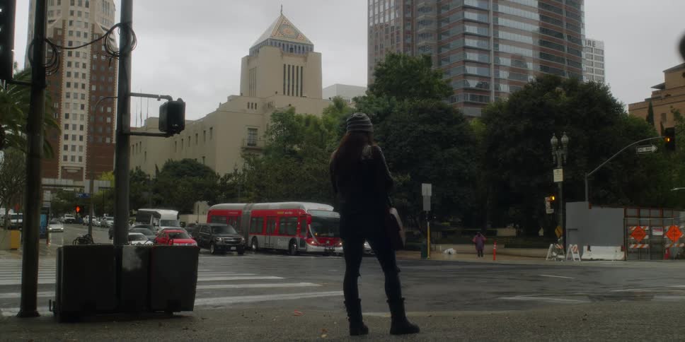 A woman waits at a city intersection to cross the street