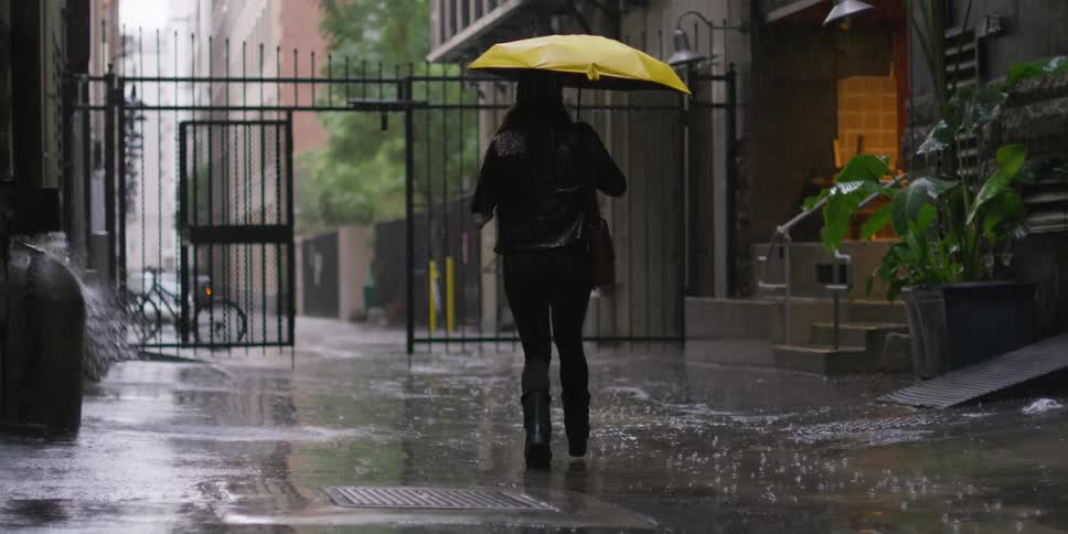 A woman runs down neighborhood street with an umbrella in the rain