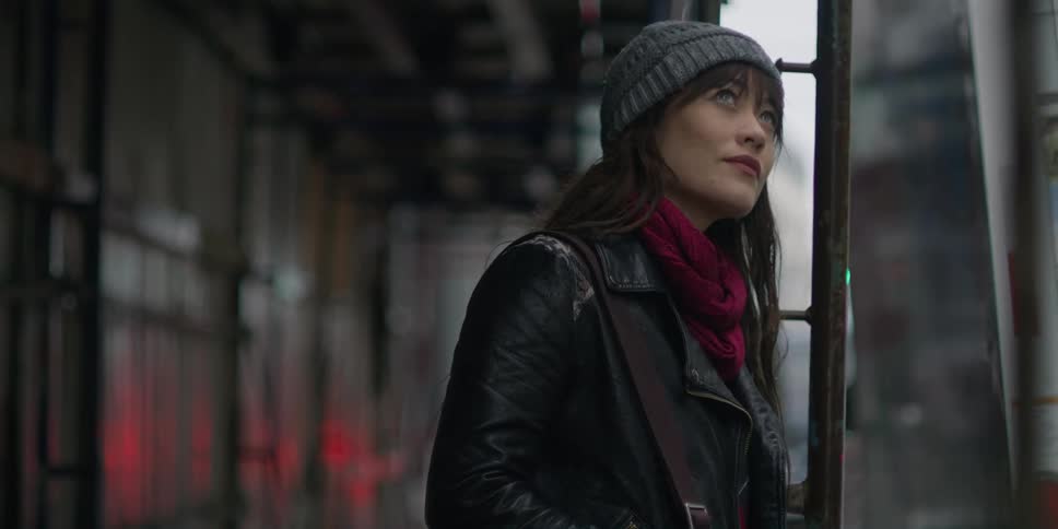 A woman is standing by a building in a downtown city