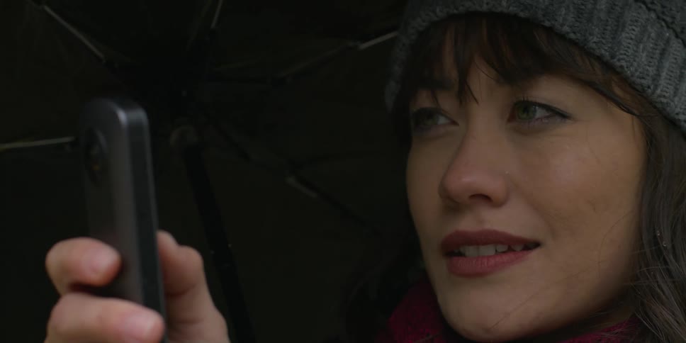 A woman holding up her camera to film while smiling softly