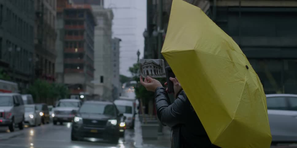 A woman stands on the corner as traffic passes