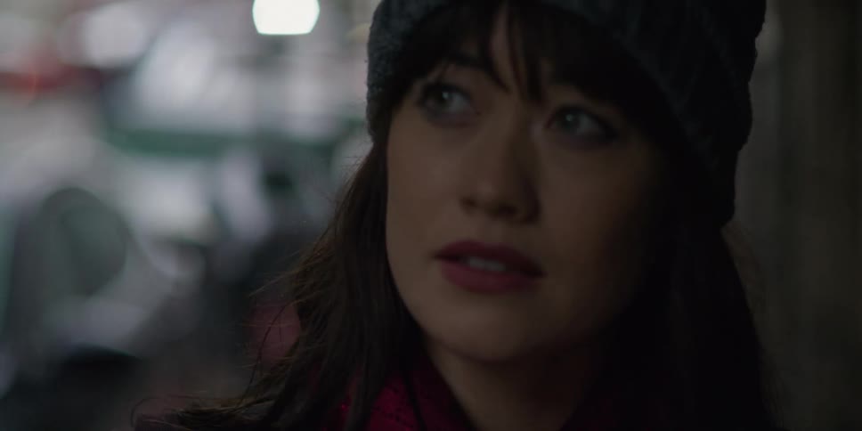 A woman wearing a knit cap is walking on a sidewalk near a street