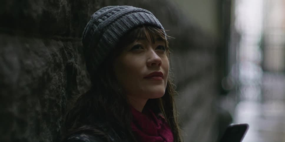 A woman standing in a city alley with her phone