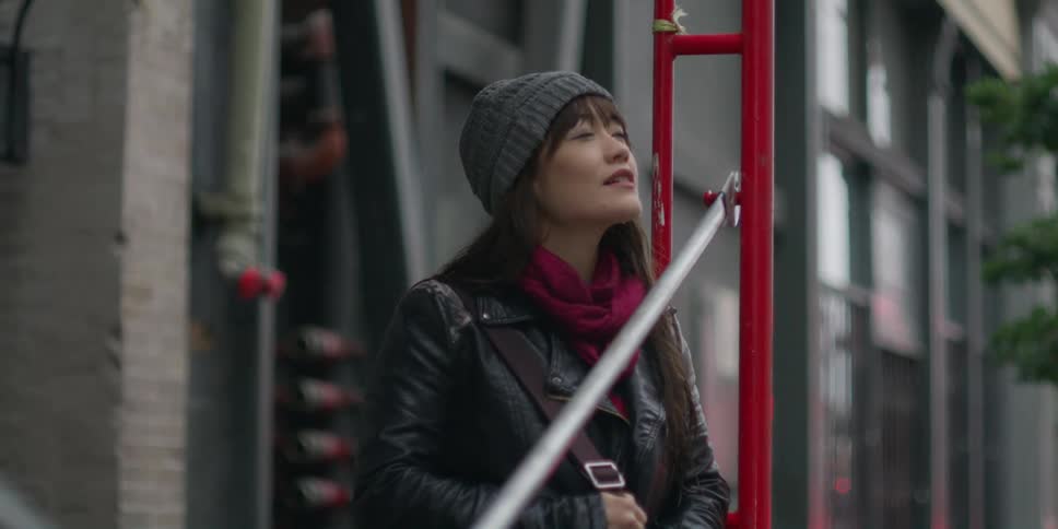 A woman bundled up standing in a city and looking into the distance