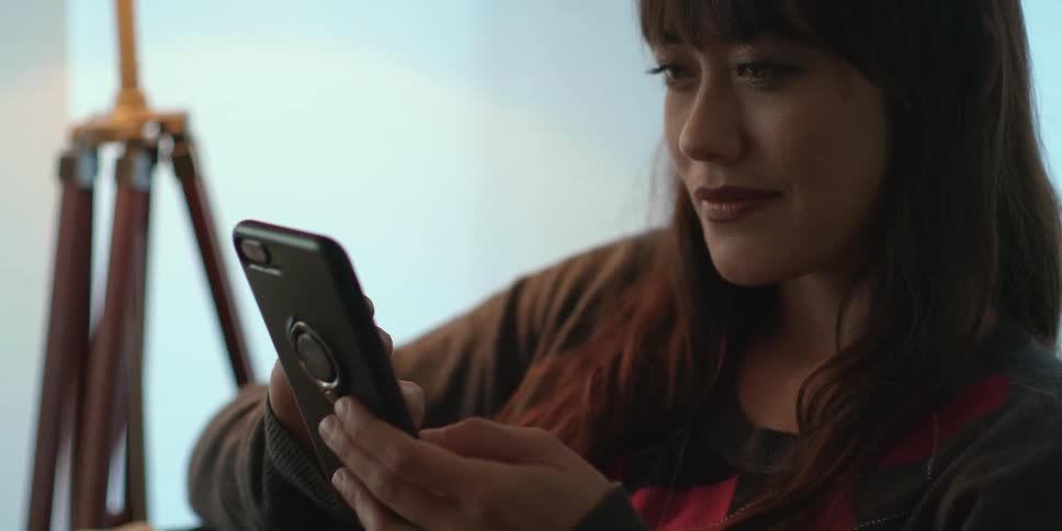 A woman smiles as she uses her cell phone