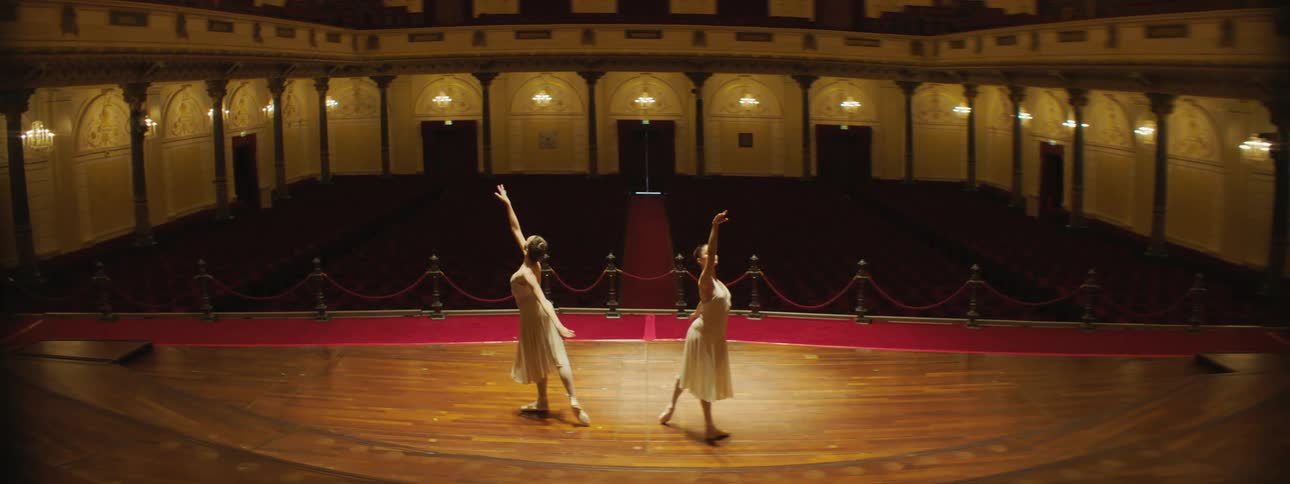 Two women in white dresses dancing on stage