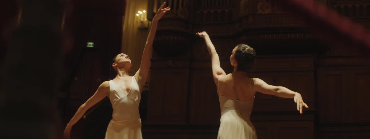 Two ballerinas dressed in white perform in theater