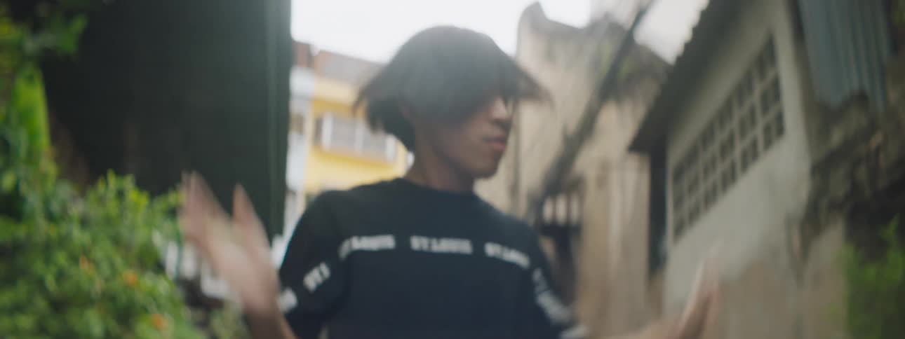 A teenage boy dancing in an alley in a neighborhood