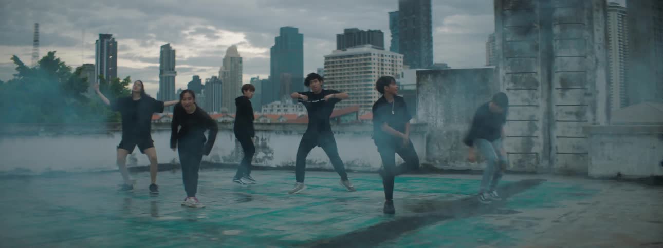 A group of teenagers dance on a rooftop building