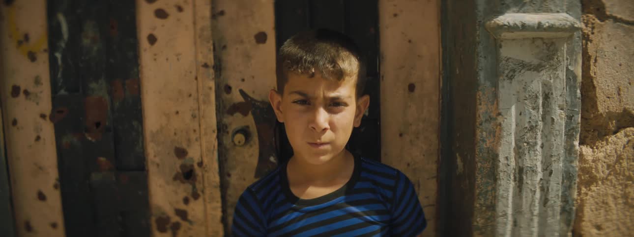 Boy stands against door of building with detailed columns