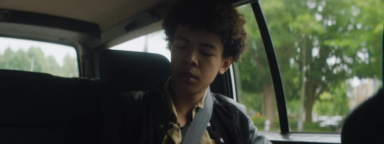 Youth sits in back seat of car moving through town