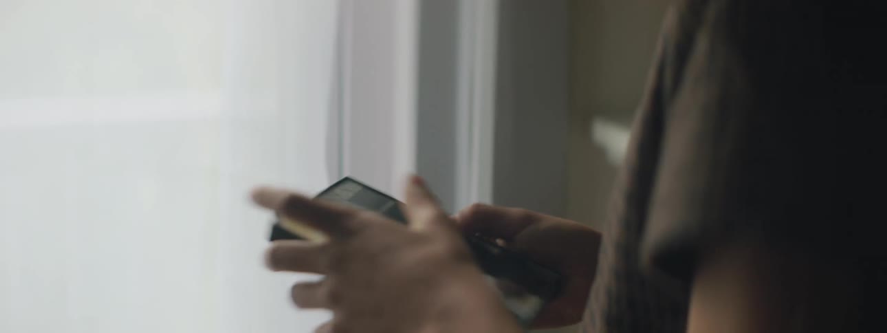 A young girl at home takes a photo off the mantle and rubs it on her shirt and looks at it