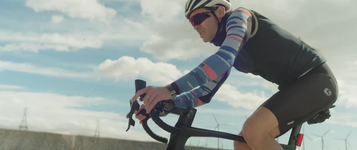 Man rides a bicycle on a desert close to wind turbines