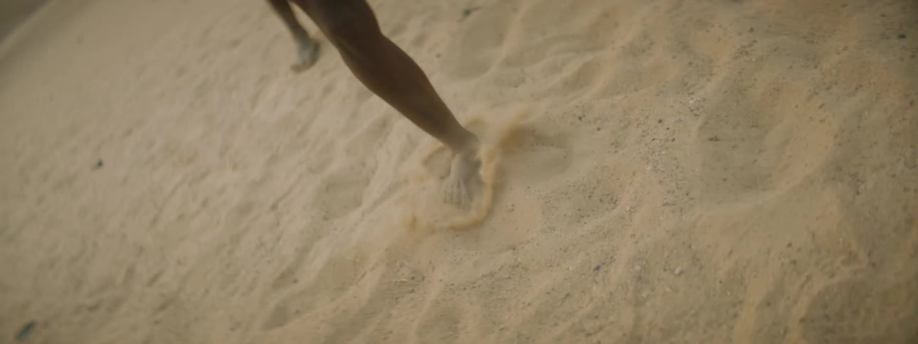 A man dances in the desert as members of his tribe clap along
