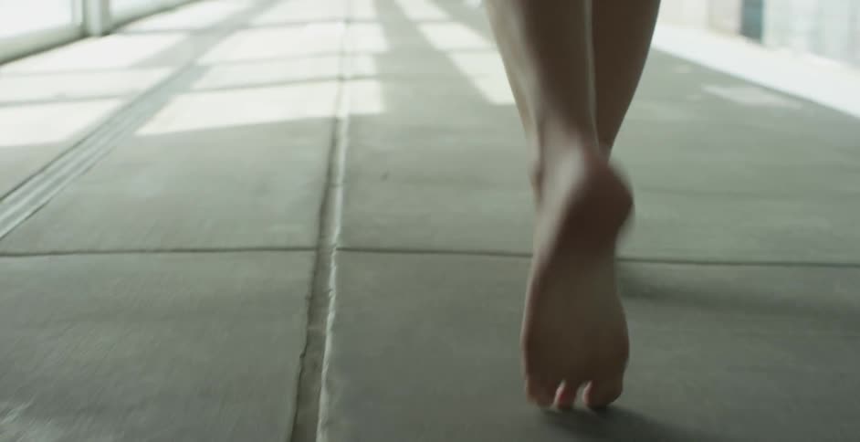 A barefoot person walks on concrete