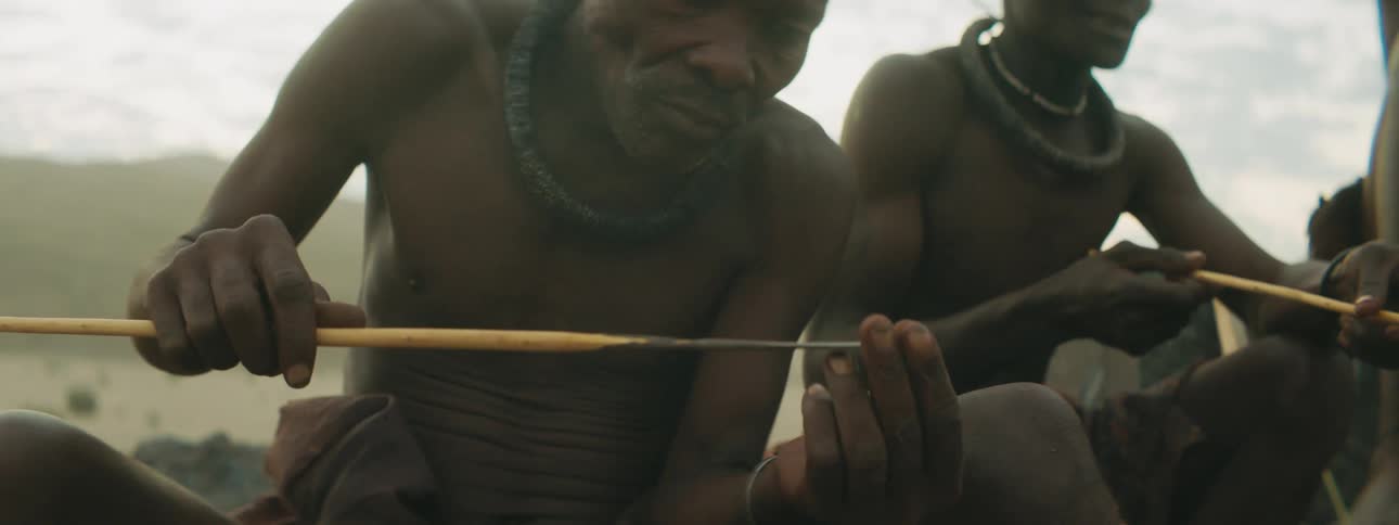 Men in a tribe examine arrows