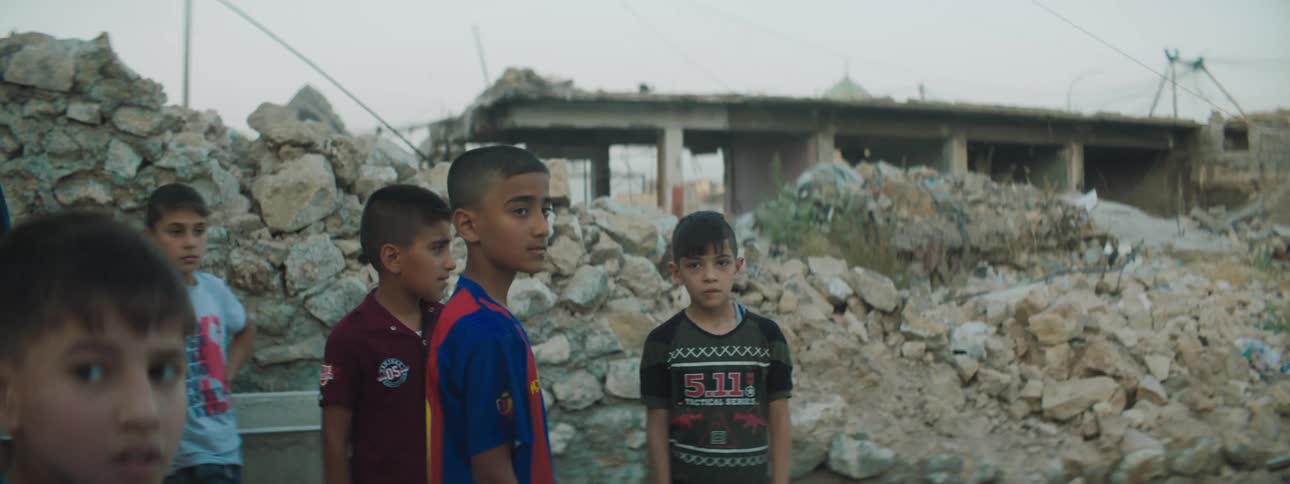 A group of young boys hang out near a pile of rubble in a developing city