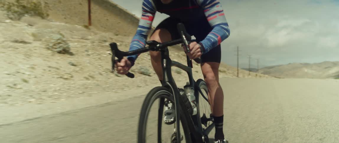 A man riding a bicycle on a desert road in the daytime