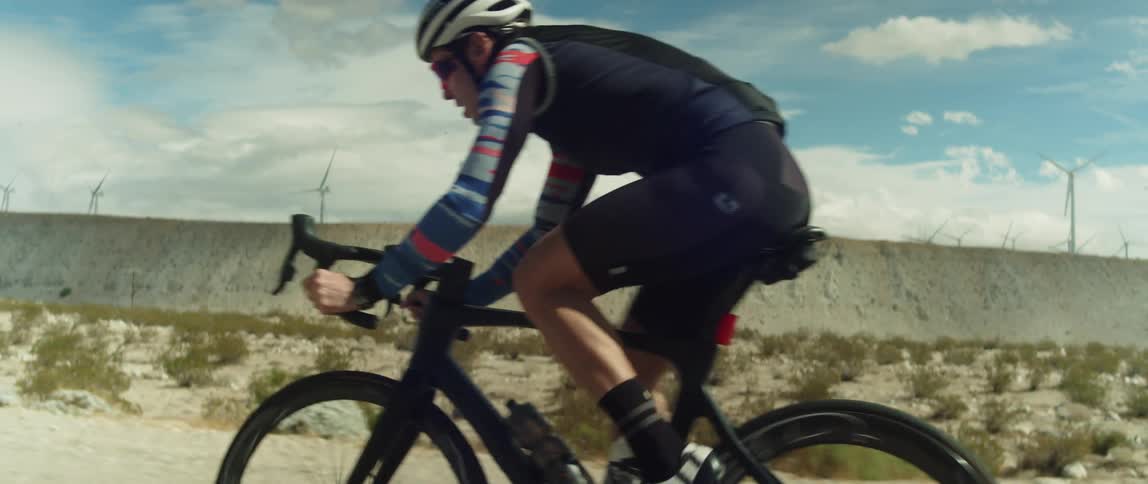 Cyclist rides through scrub passing wind farm
