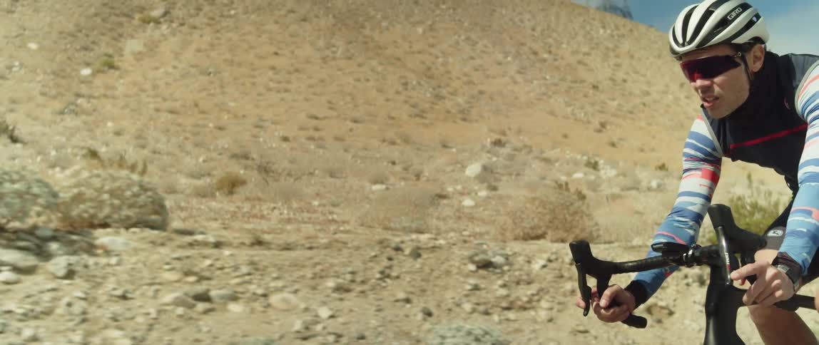 A man is braking as he rides his bike in the high desert