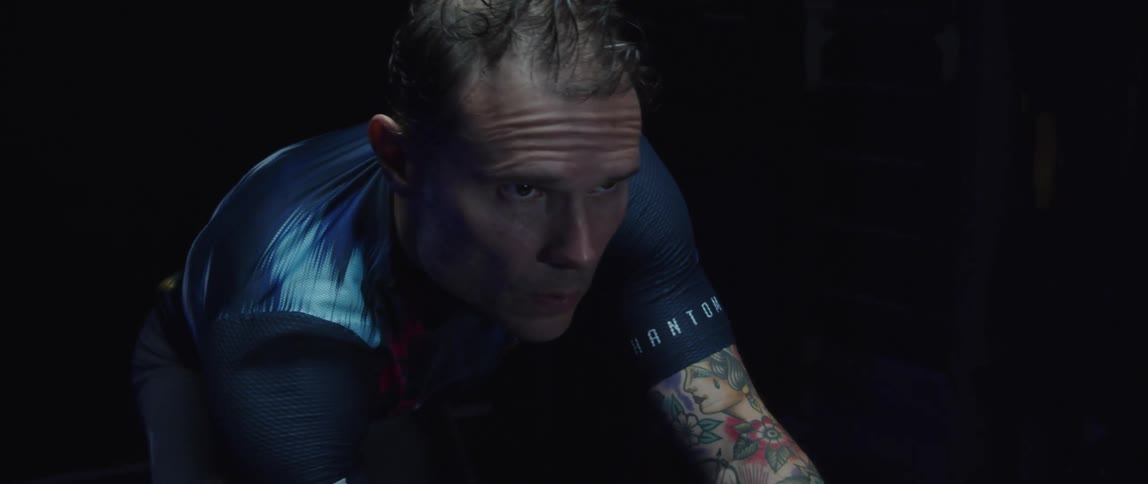 A man riding a stationary bike in a dark room