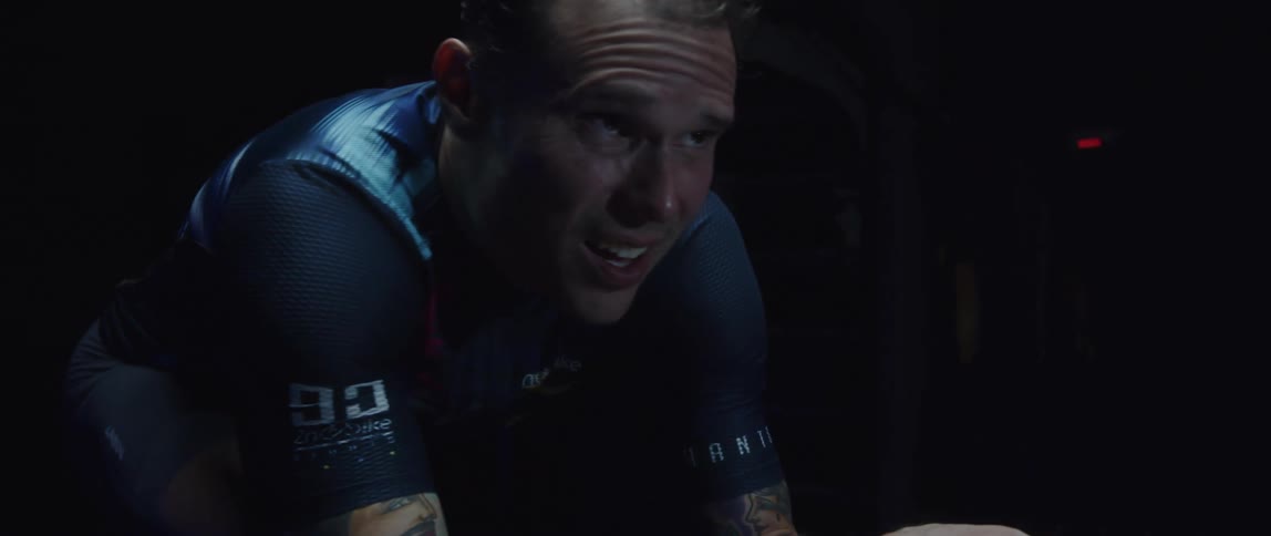 Man exercises on stationary bicycle in a dark room