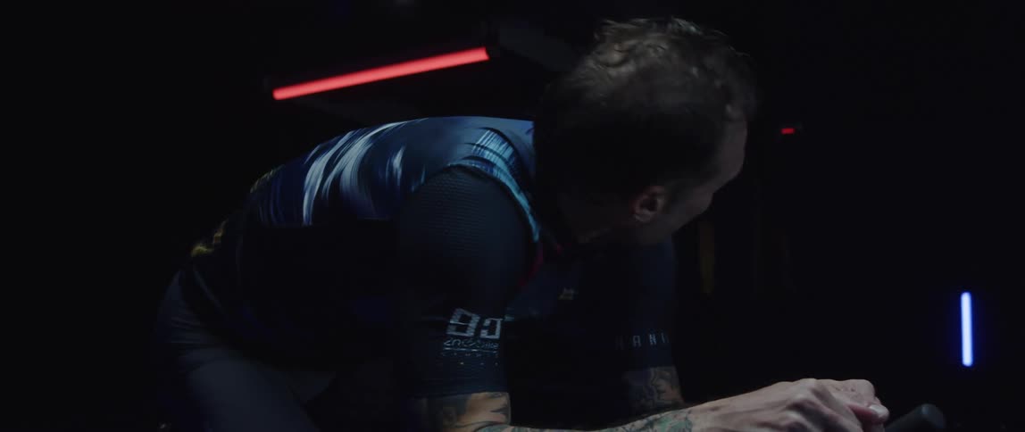 A man shaking his head while riding a stationary bike during an intense workout