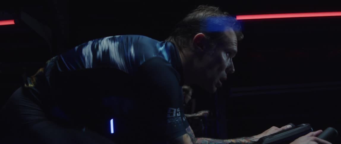 A man exercises on an exercise bike in a dark room