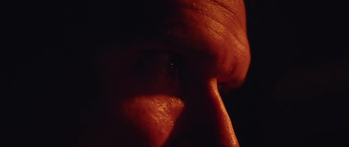 Close up of the eyes and forehead of a man inside a dimly lit room