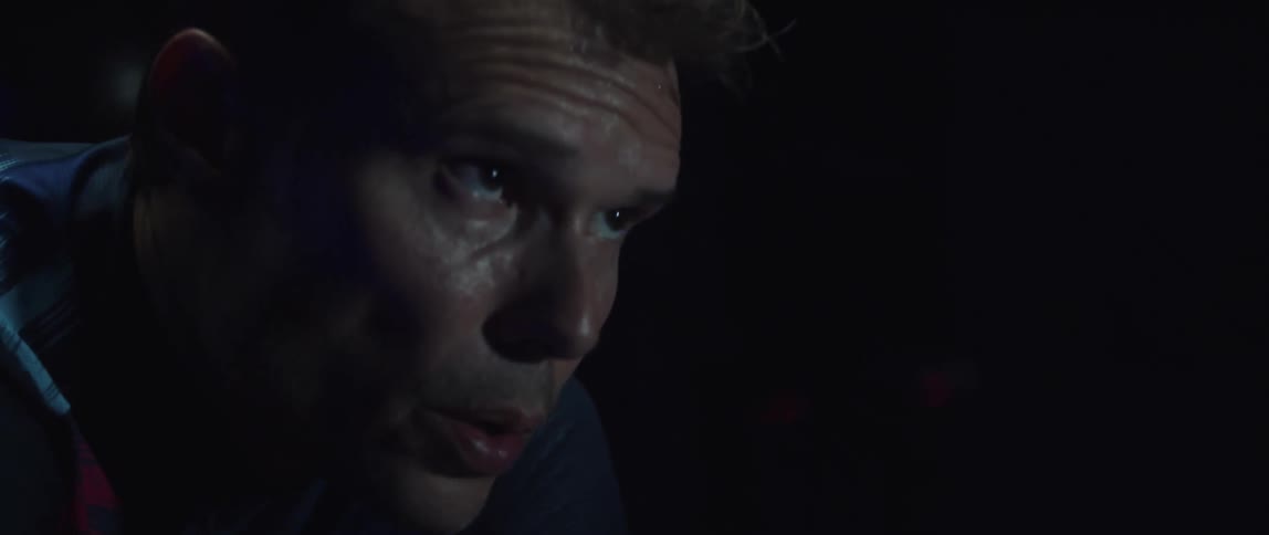 A man sweats and bows his head with the strain of pedaling while working out