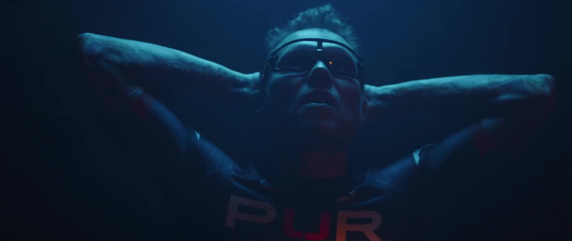 Man wearing protective glasses looks up inside a room under blue lights