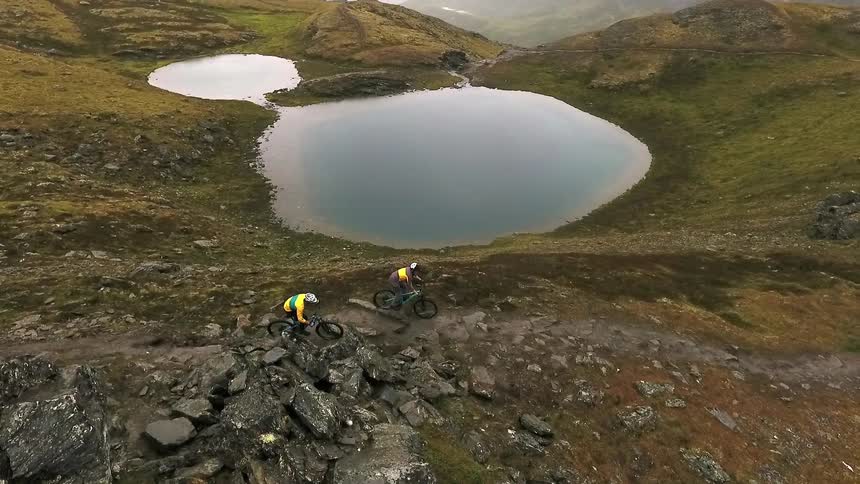 Men ride mountain bikes down a rough trail