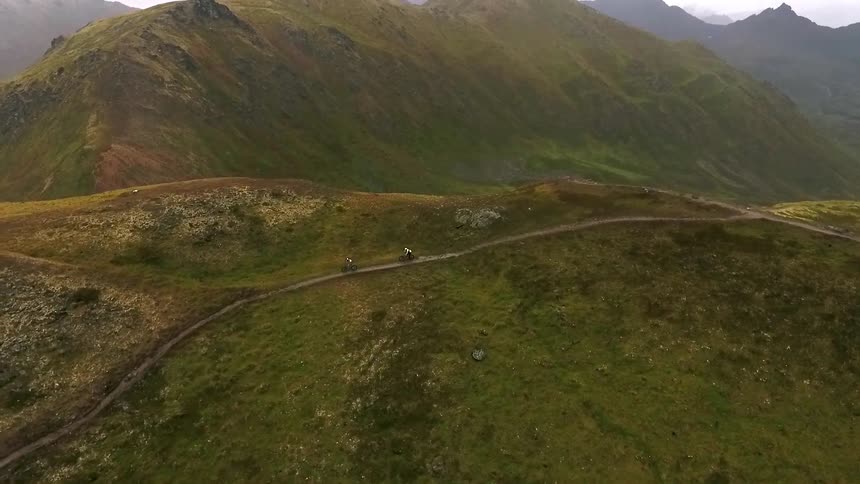 Two people ride bikes down a path