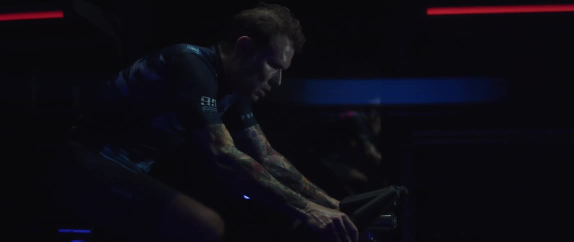 A man exercises on a exercise bike in a dark room