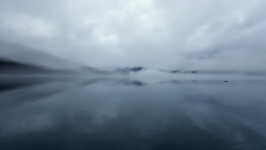 A lake is covered with fog on a cloudy day