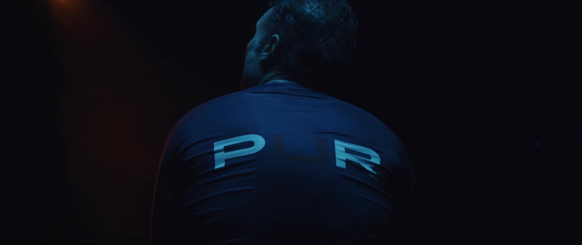 Man clasps his hands behind his neck then breathes deeply while turning to one side and looking up to stretch his neck